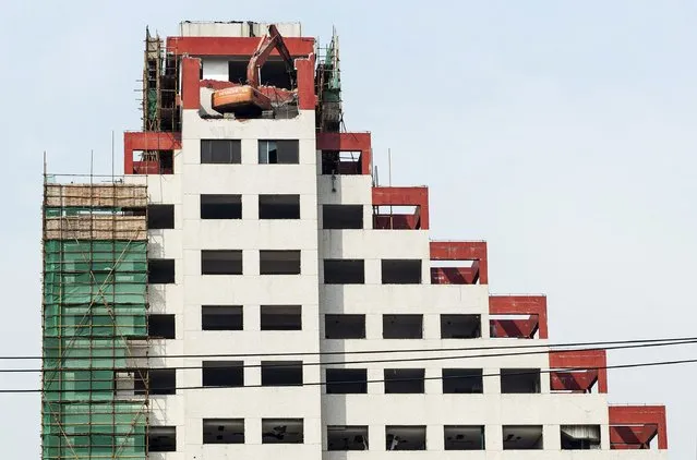 An excavator is seen atop a building being demolished in Shanghai, February 6, 2015. Weighed down by a cooling property market, industrial overcapacity and slowing investment, China's economy grew at its slowest pace in 24 years in 2014 and is expected to cool further to around 7 percent this year, even with additional stimulus. (Photo by Reuters/Stringer)