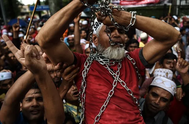 Ethnic Rohingya Muslim refugees shout slogans as they carry a man in chains during a protest against the persecution of Rohingya Muslims in Myanmar, outside the Myanmar Embassy in Kuala Lumpur on November 25, 2016. Around 5,000 Bangladeshi Muslims demonstrated in the capital Dhaka after Friday prayers on November 25, with hundreds more protesting in Kuala Lumpur, Jakarta and Bangkok as Myanmar faced mounting allegations of ethnic cleansing and genocide. (Photo by Manan Vatsyayana/AFP Photo)