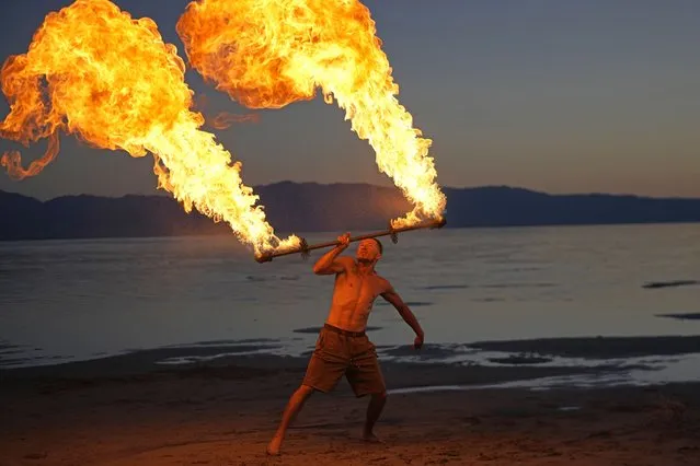 Tyler Oborn fire spins at a gathering of dancers and performers on the shoreline of the Great Salt Lake on June 15, 2023, in Magna, Utah. Oborn, who also works at a pontoon boat tour company, said the lake’s rise has given communities that rely on it new life. (Photo by Rick Bowmer/AP Photo)