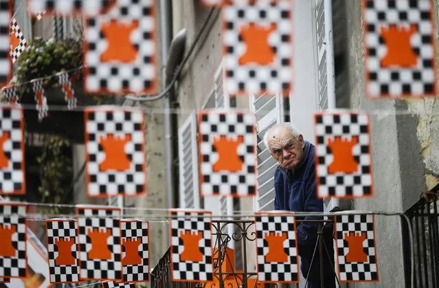 A man watches from his window as members of rival teams prepare to fight with oranges during an annual carnival battle in the northern Italian town of Ivrea February 15, 2015. (Photo by Max Rossi/Reuters)
