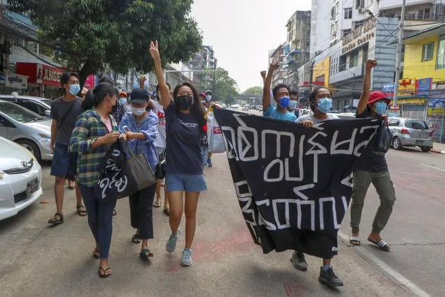 Anti-coup protesters shout slogan with a banner reading “Carry on revolution! We do not accept as the military slave”, in Kamayut township of Yangon, Myanmar, Monday, April 19, 2021. Anti-coup protesters kept public demonstrations going despite the threat of lethal violence from security forces. (Photo by AP Photo/Stringer)