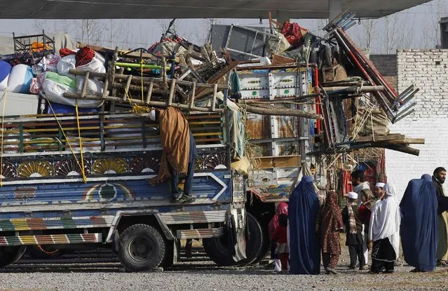 An Afghan refugee family stands by trucks loaded with their belongings as they wait to go back to Afghanistan with others, at the United Nations High Commissioner for Refugees (UNHCR) office on the outskirts of Peshawar February 13, 2015. (Photo by Fayaz Aziz/Reuters)