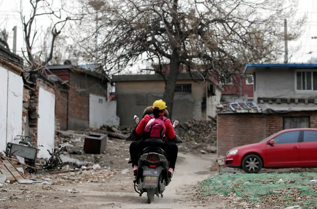 A woman rides an electric bike, carrying her daughter home in an old residential area in central Beijing, China November 29, 2016. (Photo by Jason Lee/Reuters)