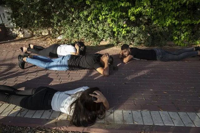 Israelis take cover as a siren sounds a warning of incoming rockets fired from the Gaza Strip, in Ashkelon, southern Israel, Sunday, May 16, 2021. (Photo by Heidi Levine/AP Photo)