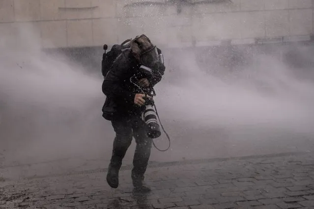 Getty Images photographer John Moore gets hit by a water cannon during clashes with riot police at a rally-march ahead of the 50th anniversary of the 1973 Chilean military coup, in Santiago, Chile on September 10, 2023. (Photo by Carlos Barria/Reuters)