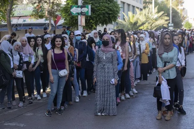 Syrian students attend to votes at a polling station during the Presidential elections in the Syrian capital Damascus, Syria, Wednesday, May 26, 2021. (Photo by Hassan Ammar/AP Photo)