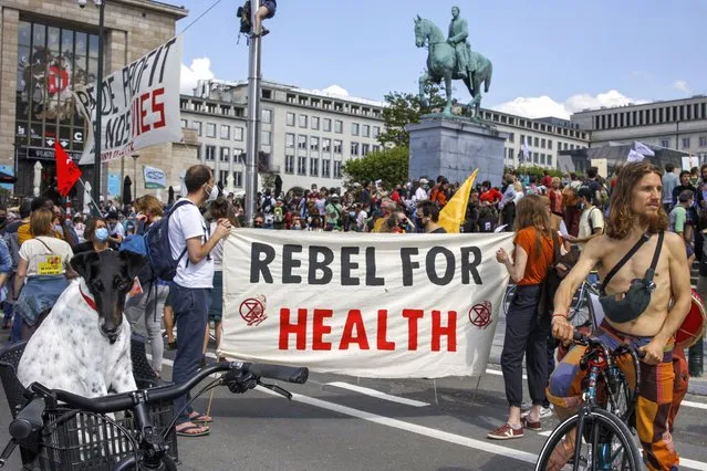 People, most of them wearing protective face masks, gather during a healthcare workers' protest in downtown Brussels, Saturday, May 29, 2021. Protesters gathered to defend the healthcare system services and demanded more workers, better work conditions and bigger budged. (Photo by Olivier Matthys/AP Photo)
