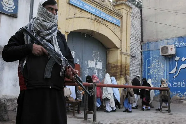 Security guards stand alert around schools and colleges following an attack on Bacha Khan University, in Peshawar, Pakistan, Thursday, January 21, 2016. Pakistanis buried their dead and observed a day of nationwide mourning Thursday following the brazen attack by Islamic militants who stormed a northwestern university the previous day, gunning down students and teachers and spreading terror before the four gunmen were slain by the military. (Photo by Mohammad Sajjad/AP Photo)