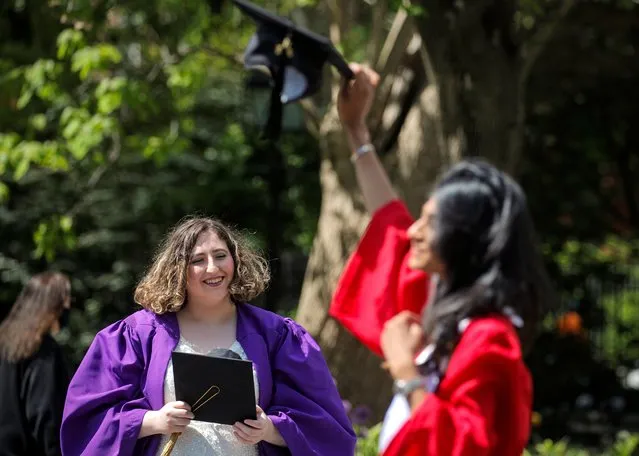 A graduate of New York University looks on as a graduate of The New School poses under the Washington Square Arch in Washington Square Park in New York City, May 13, 2021. (Photo by Brendan McDermid/Reuters)