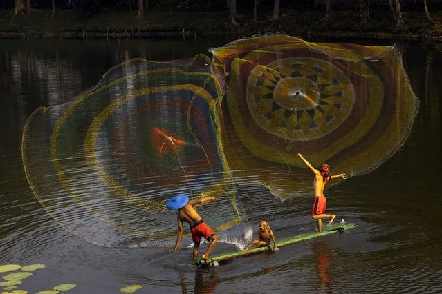 These fishermen create a colourful display as they throw out nets to catch fish on a lake in Bogor, West Java, Indonesia on September 26, 2023. (Photo by Lisdiyanto Suhardjo/Solent News & Photo Agency)