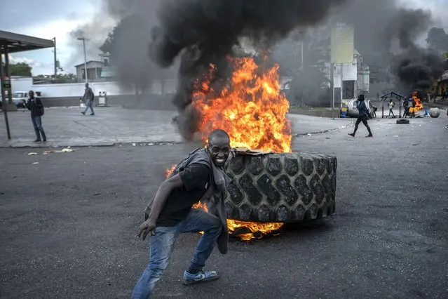 A protester adds a tire to a burning barricade during a protest against fuel price hikes and demands for Haitian Prime Minister Ariel Henry to step down in Port-au-Prince, Haiti, Friday, September 16, 2022. (Photo by Joseph Odelyn/AP Photo)