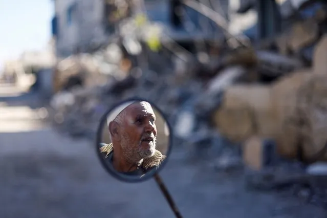 A man's face is reflected in a mirror, near the ruins of houses destroyed in Israeli strikes during the conflict, during a temporary truce between Hamas and Israel, in Khan Younis in the southern Gaza Strip on November 30, 2023. (Photo by Mohammed Salem/Reuters)