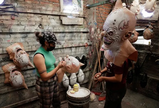 Yareli Perez paints a mask for upcoming Halloween celebrations at a workshop in Yehualtepec, Mexico on October 12, 2022. (Photo by Imelda Medina/Reuters)