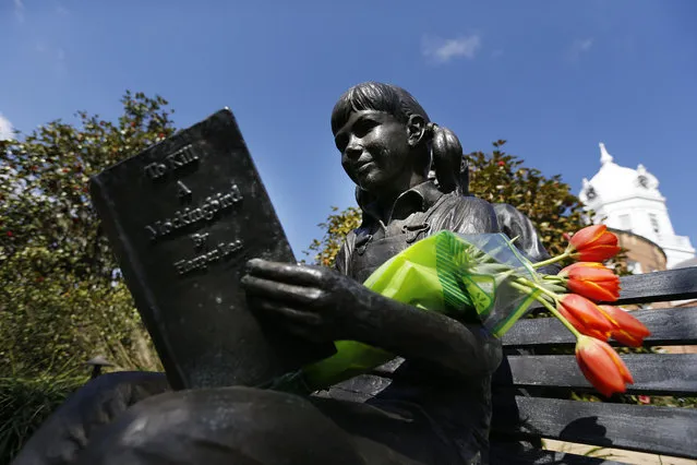 Flowers are placed on a statue of a girl reading Harper Lee's “To Kill a Mockingbird”, in memorial of Lee, Friday, February 19, 2016, in Monroeville, Ala. Lee, the elusive author of the best-selling classic, died Friday, according to her publisher Harper Collins. She was 89. (Photo by Brynn Anderson/AP Photo)