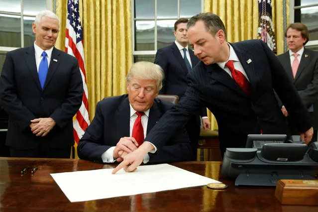 White House Chief of Staff Reince Priebus (R) directs U.S. President Donald Trump, flanked by Vice President Mike Pence (L), where to sign the document to confirming James Mattis his Secretary of Defense, his first signing in the Oval Office in Washington, U.S. January 20, 2017. (Photo by Jonathan Ernst/Reuters)