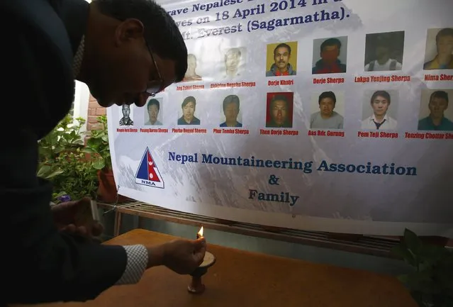 A man lights butter lamp in front of the portraits of 16 Nepali Sherpa guides, who were killed during an avalanche last year, during an event organised in memory of the Sherpas in Kathmandu April 18, 2015. (Photo by Navesh Chitrakar/Reuters)