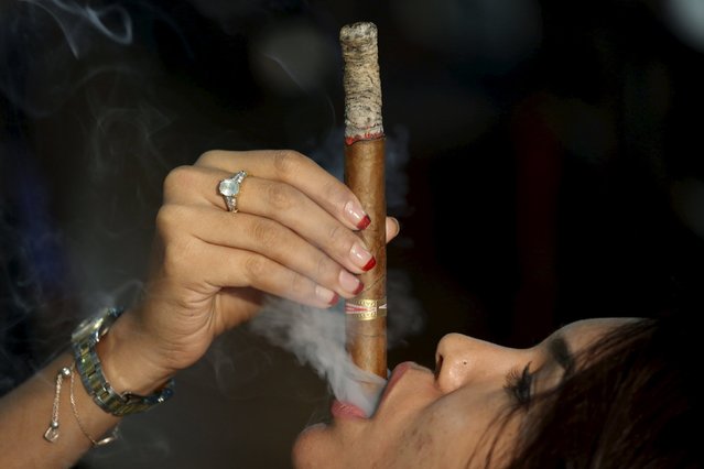 Francis Sierra, 23, smokes as she competes for the longest ash during the XVIII Habanos Festival in Havana, March 3, 2016. (Photo by Alexandre Meneghini/Reuters)