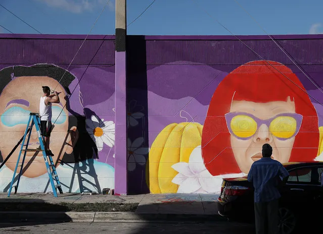 Winston Farrar helps paint a mural by artist, Cloe Hakakian, on the side of a building, as the Wynwood neighborhood prepares for the annual Art Basel art fair on December 03, 2018 in Miami, Florida. Artists and art lovers from around the world flock to the Miami area from Dec. 6 to the 9th to visit Art Basel as well as the satellite galleries that pop up throughout the city during the week. (Photo by Joe Raedle/Getty Images)