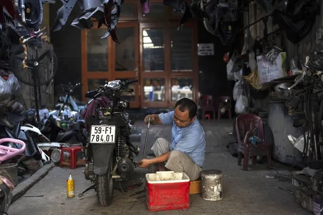 A mechanic works on a scooter at a repair shop in Ho Chi Minh City, Vietnam, January 13, 2024. (Photo by Jae C. Hong/AP Photo)