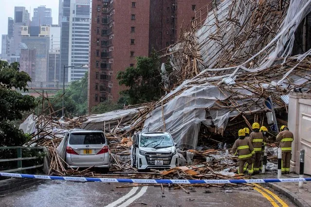 Rescue personnel at the scene where bamboo scaffolding by a high-rise residential building collapsed onto a road, following strong winds and heavy rain from weather patterns from a tropical storm, in Hong Kong on October 8, 2021. (Photo by Isaac Lawrence/AFP Photo)