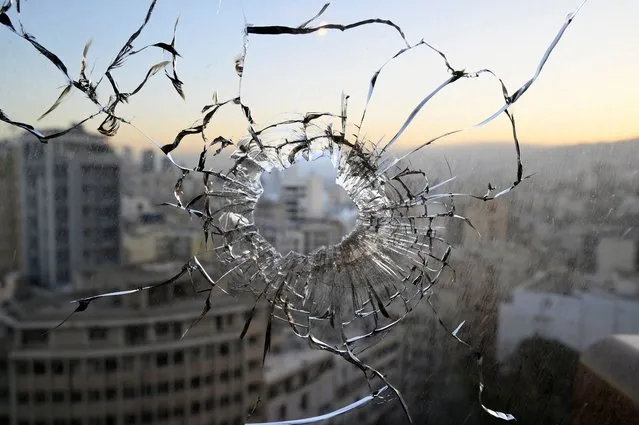 A gun hole is seen on a window at a building a day after clashes in the area of Tayouneh in Beirut, Lebanon, 15 October 2021. At least six people were killed and 20 wounded at a Beirut rally organized by Hezbollah and Amal movements to demand the dismissal of the Beirut blast lead investigator. (Photo by Wael Hamzeh/EPA/EFE)