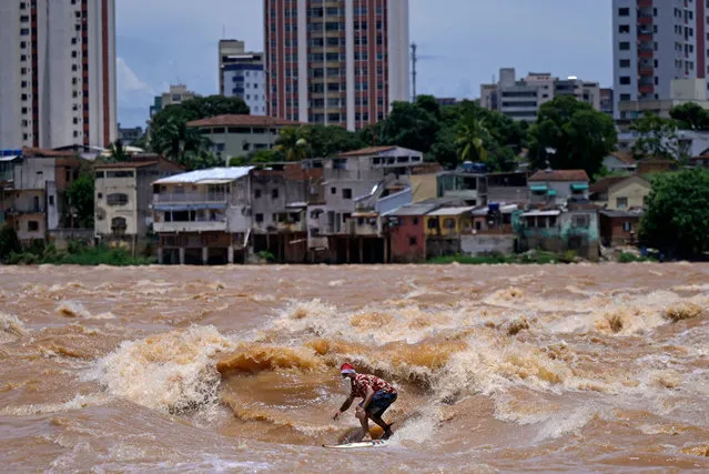 Brazilian surfer Paulo Guido surfs the Doce River while wearing a Christmas outfit in Governador Valadares, Minas Gerais state, Brazil, on December 10, 2022. Minas Gerais is a state in the southeastern region of Brazil that is not bathed by the sea, but even so, Paulo Guido found a way to practice the sport he loves close to home. (Photo by Douglas Magno/AFP Photo)