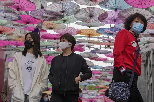 Visitors wearing face masks walk under colorful umbrellas on display along a hutong alley near Qianmen Avenue, a popular tourist spot in Beijing, Thursday, October 14, 2021. (Photo by Andy Wong/AP Photo)