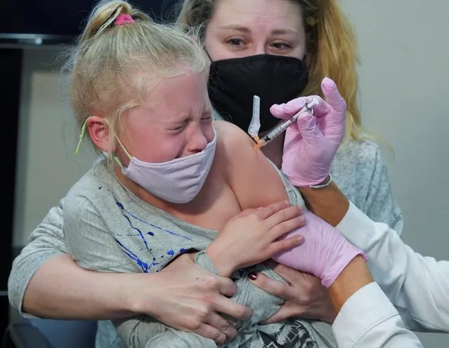 Emma Ingle, 7, sitting on her mother Kim Obert's lap, receives her first dose of the Pfizer-BioNTech coronavirus vaccine (COVID-19) in Storrs, Connecticut, U.S., November 3, 2021. (Photo by Michelle McLoughlin/Reuters)