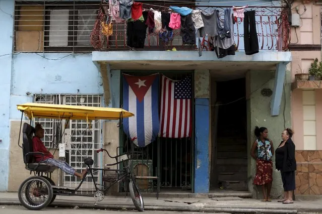 Women are seen in front a house adorned with flags of U.S. and Cuba on the outskirts of Havana, Cuba March 21, 2016. (Photo by Ueslei Marcelino/Reuters)