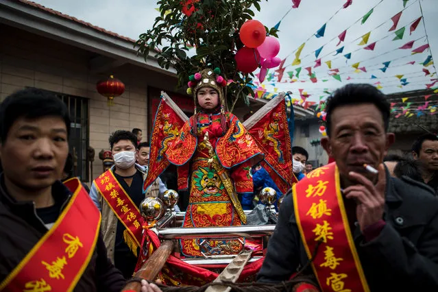 This picture taken on February 9, 2017 shows locals carrying children in palanquins as they parade during a festival in the village of Tufang in eastern China' s Fujian province It' s an annual event in the village of Tufang in coastal Fujian province, where China' s Hakka community is concentrated and marks its unique history with a range of festivals. The Hakka, which means “guest”, are Chinese who speak their own eponymous dialect and have a history as wanderers that has given birth to a range of colourful cultural rituals. (Photo by Johannes Eisele/AFP Photo)