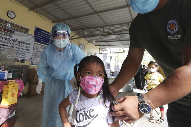 A young girl, center, receives a shot of the Sinovac's COVID-19 vaccine at a Krang Thnong health center outside Phnom Penh, Cambodia, Monday, November 1, 2021. Cambodia on Monday began vaccinating 5-year-old children against the coronavirus as its leader announced the official reopening of the country, including the phased reentry of tourists. (Photo by Heng Sinith/AP Photo)