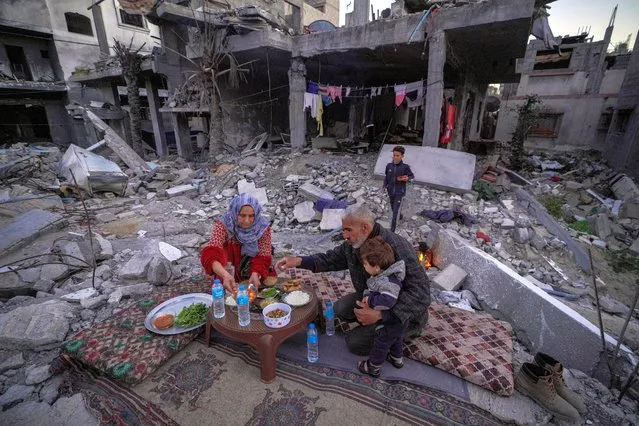 The Palestinian Al-Naji family prepare to break their fast during the first day of the Muslim holy fasting month of Ramadan sitting amidst the ruins of their family house in Deir el-Balah, central Gaza Strip, on March 11, 2024, amid ongoing battles between Israel and the militant group Hamas. (Photo by AFP Photo)