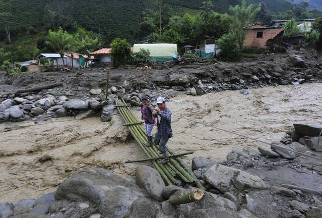 Residents cross over an improvised bridge after a landslide sent mud and water crashing onto homes close to the municipality of Salgar in Antioquia department, Colombia May 19, 2015. (Photo by Jose Miguel Gomez/Reuters)