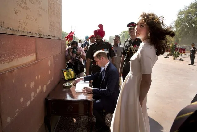 Britain's Prince William, signs visitor's book  as his wife Kate, the Duchess of Cambridge looks on after paying their tributes at the India Gate war memorial, in the memory of the soldiers from Indian regiments who served in World War I, in New Delhi, India, Monday, April 11, 2016. (Photo by Manish Swarup/Pool Photo via AP Photo)