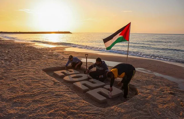 Palestinian youths sculpt the number 2022 in the sand at sunset ahead of new year's eve, at the beach in the coastal Mediterranean city of Gaza, on December 28, 2021. (Photo by Mohammed Abed/AFP Photo)