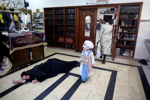 An ultra-Orthodox Jewish boy dressed in a costume walks past a drunk man lying on the floor during an annual parade marking the Jewish holiday of Purim, in Jerusalem March 13, 2017. (Photo by Nir Elias/Reuters)