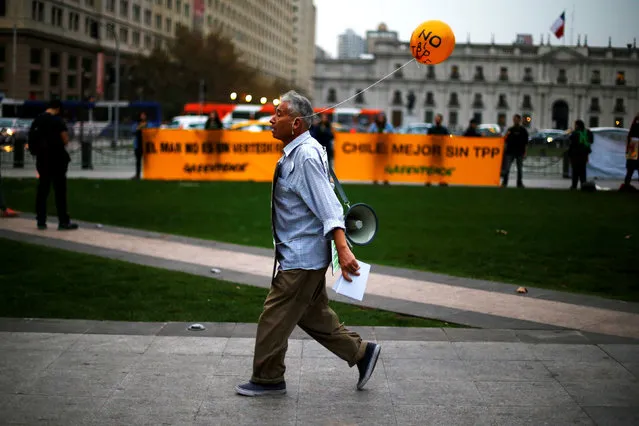 A man carries a balloon tied to his ear that reads “No to TPP” during a rally against the Trans-Pacific Partnership (TPP) trade deal in front of the government house at Santiago, Chile, May 9, 2016. (Photo by Ivan Alvarado/Reuters)