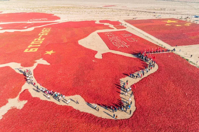 This aerial photo taken on September 23, 2019 shows the image of a Chinese map and a national flag formed by dried chili peppers during the harvest season in Zhangye in China's northwestern Gansu province, as farmers celebrate the 70th anniversary of the founding of the People's Republic of China. (Photo by AFP Photo/China Stringer Network)