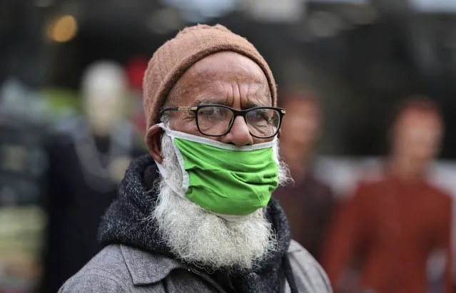 An elderly man wears his face mask below his nose and walks in a market area in Jammu, India, Saturday, January 15, 2022. (Photo by Channi Anand/AP Photo)