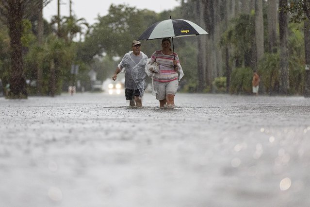 Jim Comunale and Pam Mervos walk down Arthur Street as heavy rain floods the surrounding neighborhood on Wednesday, June 12, 2024, in Hollywood, Fla. (Photo by Matias J. Ocner/Miami Herald via AP Photo)