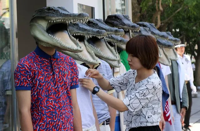 A dress fitter (R) checks clothes of models wearing masks of crocodile to show off a new French collection in Tokyo on May 30, 2015. (Photo by Yoshikazu Tsuno/AFP Photo)
