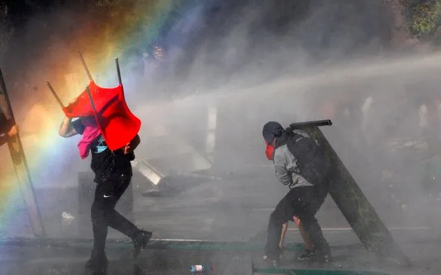 Demonstrators clash with riot police during a protest against President Sebastian Piñera on October 21, 2019 in Santiago, Chile. President Sebastian Piñera suspended the 3.5% subway fare hike and declared the state of emergency for the first time since the return of democracy in 1990. Protests had begun on Friday and developed into looting and arson, generating chaos in Santiago, Valparaiso and a dozen other cities resulting in at least 8 dead. (Photo by Marcelo Hernandez/Getty Images)