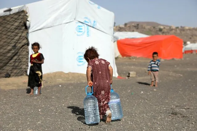 A girl carries bottles of water filled from a charity tank at a camp for internally displaced people (IDPs) near Sanaa, Yemen on March 25, 2022. (Photo by Khaled Abdullah/Reuters)