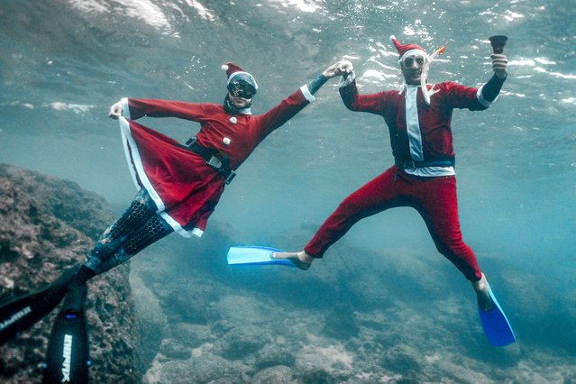 Freedivers dressed in Saint Nicholas (Santa Claus) costumes pose for a picture while submerged under water off the coast of Lebanon's northern city of Batroun on Christmas eve on December 24, 2021. (Photo by Ibrahim Chalhoub/AFP Photo)