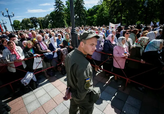 A serviceman of the National Guard stands guard as faithfuls and priests of the Ukrainian Orthodox Church of the Moscow Patriarchate attend a rally against proposed laws that would give Ukrainian authorities more control over their branch of the church in front of Ukrainian Parliament in Kiev, Ukraine, May 18, 2017. (Photo by Gleb Garanich/Reuters)