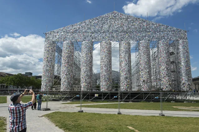 A man shoots a photo in front of the work “The Parthenon of Books” by Argentine's  artist Marta Minujin, which is under construction, in preparation for the upcoming documenta 14 art exhibition in Kassel, Germany, Sunday, May 21, 2017. The installation shows books wrapped in plastic. documenta 14 in Kassel runs from June 10, 2017, and last until Sept. 17, 2017. (Photo by Jens Meyer/AP Photo)