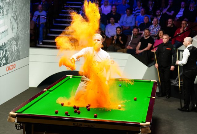 A Just Stop Oil protester jumps on the table and throws orange powder during the match between Robert Milkins against Joe Perry during day three of the Cazoo World Snooker Championship at the Crucible Theatre, Sheffield on Monday, April 17, 2023. (Photo by Mike Egerton/PA Images via Getty Images)