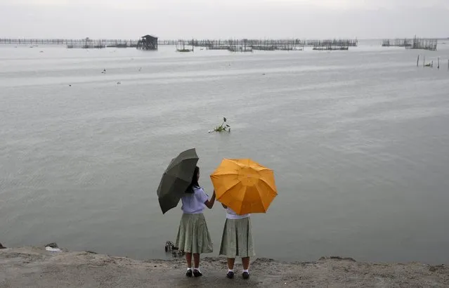 Schoolgirls with umbrellas take a stroll after classes were suspended due to bad weather, at a park in front of Laguna de Bay, in Paranaque, Metro Manila July 6, 2015. (Photo by Erik De Castro/Reuters)