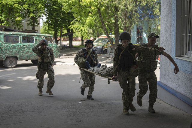 Ukrainian servicemen carry an injured comrade on A stretcher to the hospital after an attack by Russian forces in Donetsk region, Ukraine, on Monday, May 9, 2022. (Photo by Evgeniy Maloletka/AP Photo)