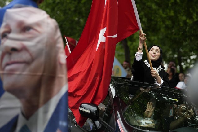 A supporter of the President Recep Tayyip Erdogan waves a Turkish flag at AK Party offices in Istanbul, Turkey, Sunday, May 28, 2023. Erdogan takes lead in unofficial count in Turkey's presidential runoff. (Photo by Khalil Hamra/AP Photo)